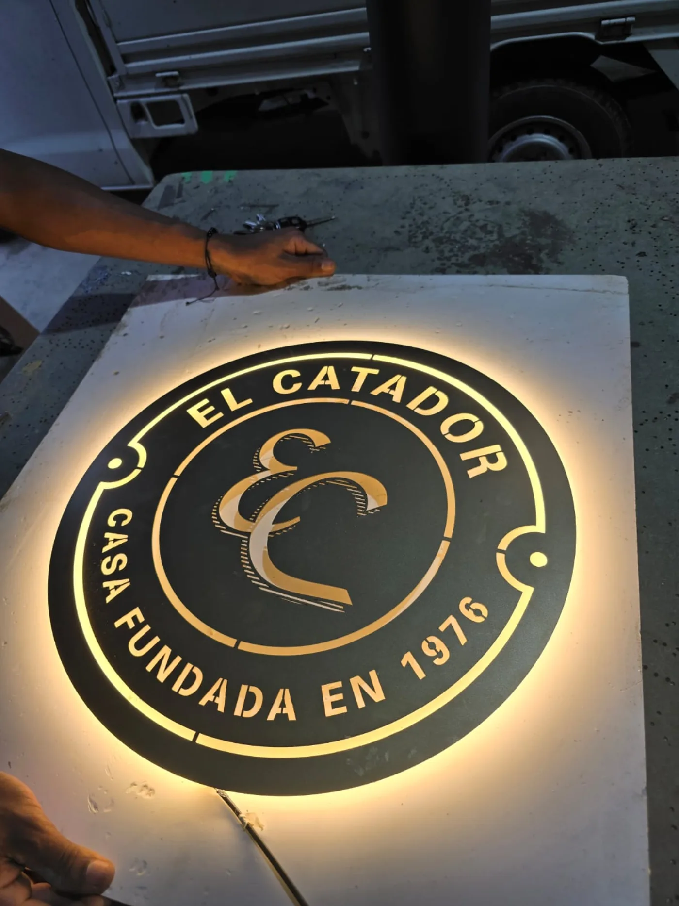 Emblema circular de El Catador retroiluminado en dorado