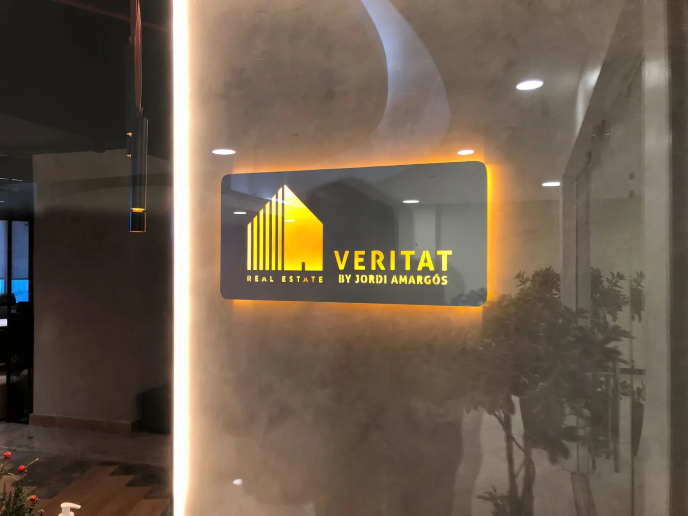 Letrero de Veritat Real Estate con iluminación de halo
